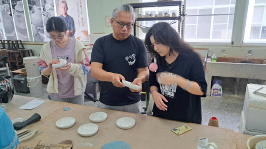 說明：苗栗工藝中心陶藝家羅志峰老師協助詹雅晴、郭芷暄燒製『疊碟』創作